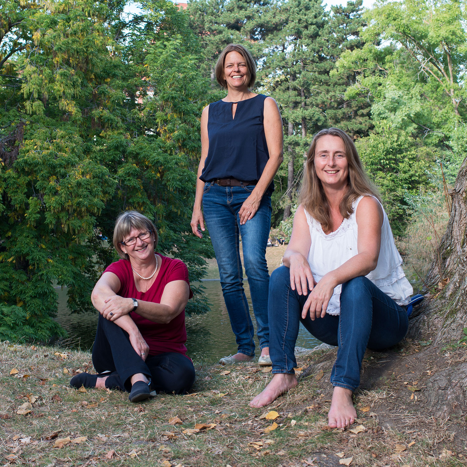 Drei Frauen sitzen oder stehen im Wald